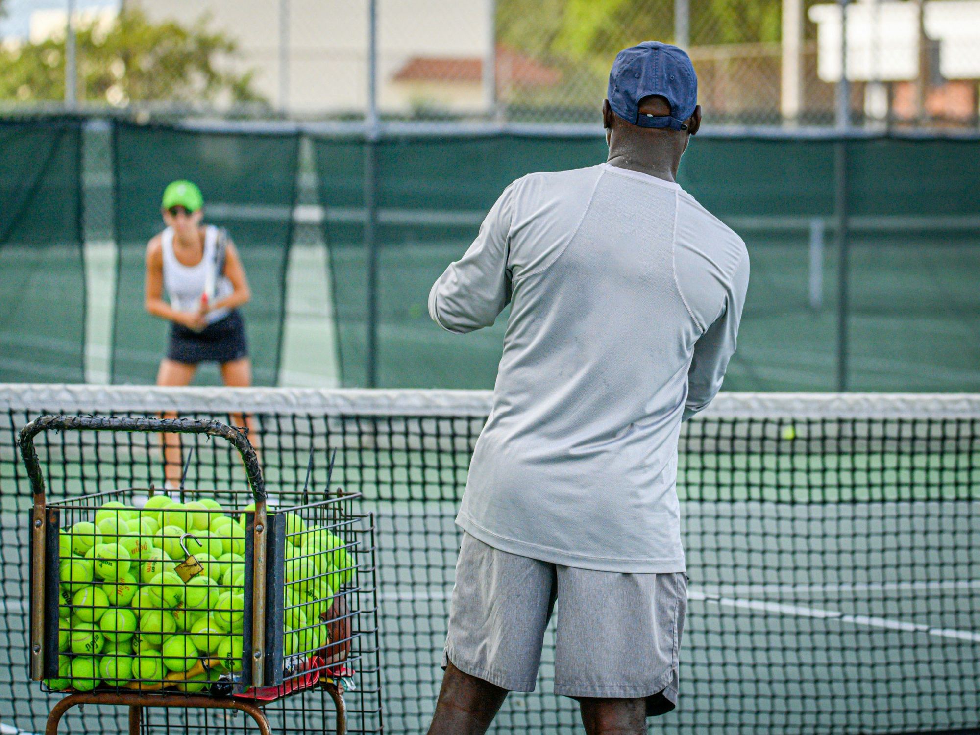 Tennis coach running a session on a U.S. academy court